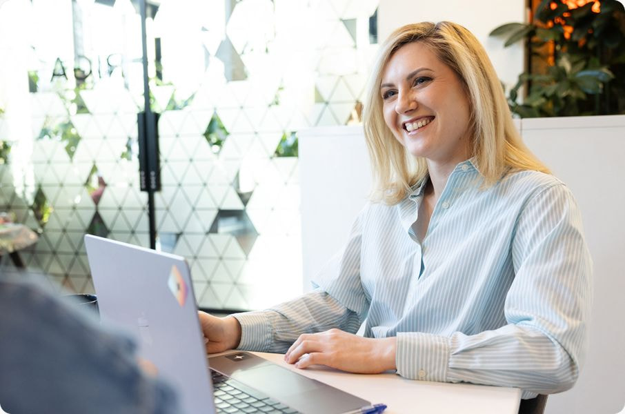 a woman smiling at a laptop