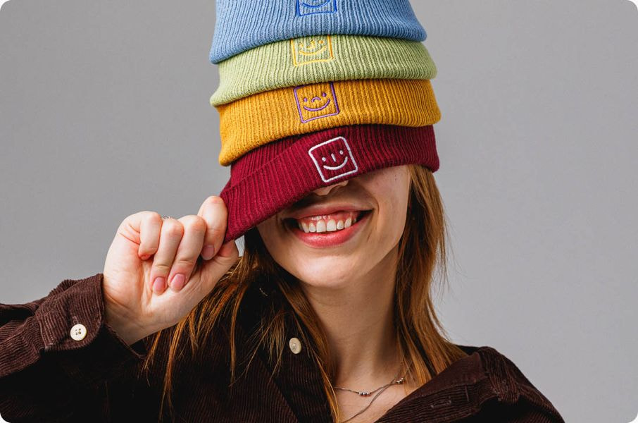 a woman covering her face with a stack of hats