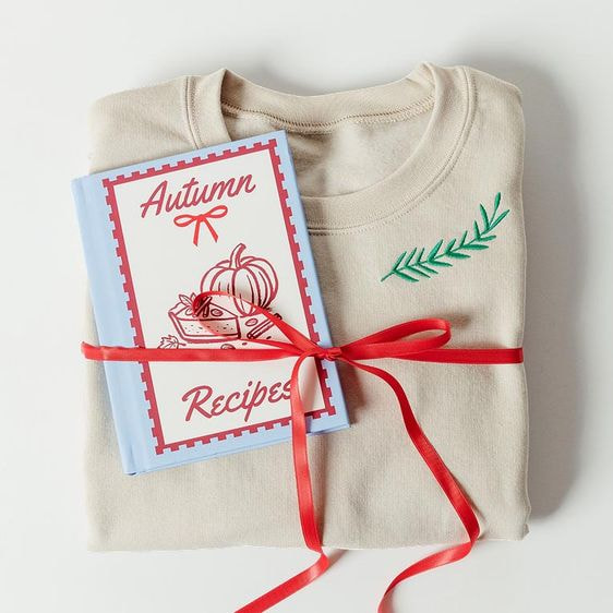 a book tied with a red ribbon on a white shirt