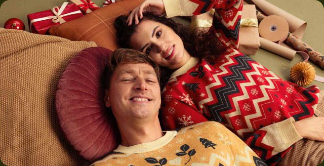 a man and woman lying on pillows and smiling